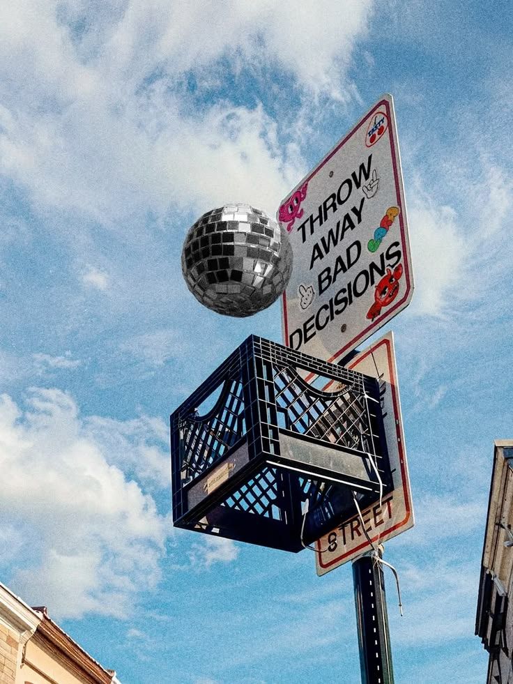 A street sign reading 'Throw away bad decisions' with a disco ball on top